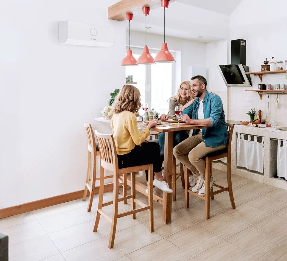 Family sitting in a modern kitchen with a wall mounted air conditioning unit